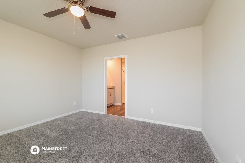 the spacious living room with carpet and ceiling fan