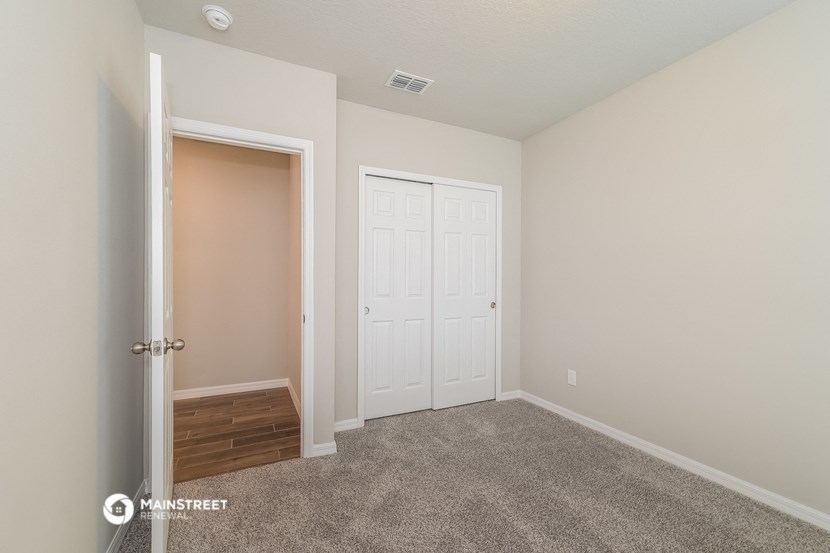 a bedroom with white doors and carpet and a door to a closet