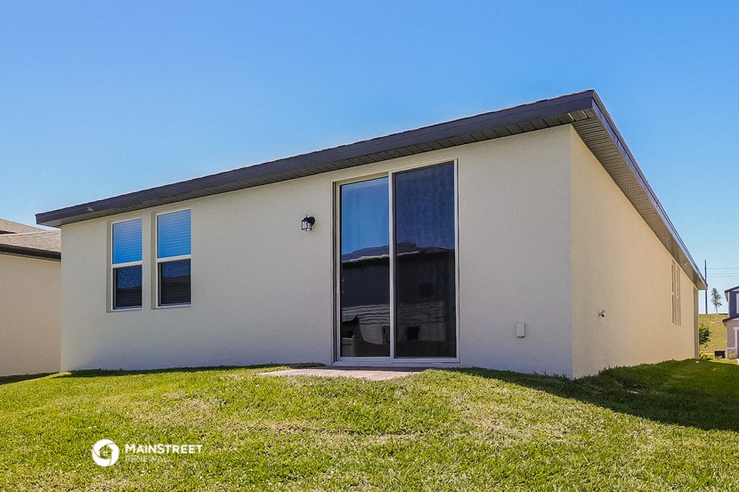 the exterior of a white house with glass doors and a lawn