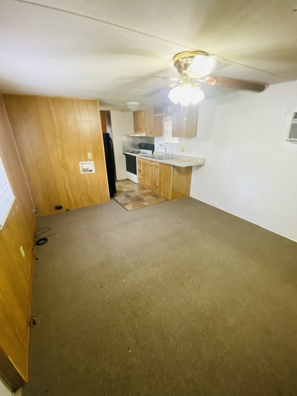 an empty living room with a kitchen in the background
