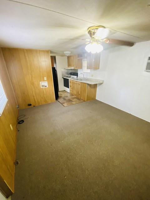 an empty living room with a kitchen in the background