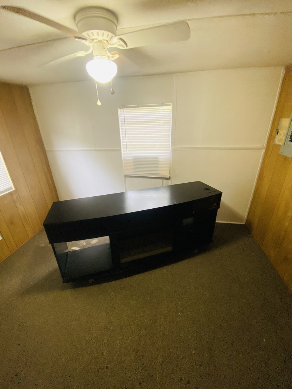 a small room with a desk and a ceiling fan
