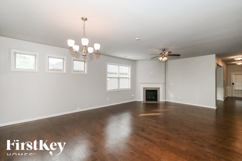 an empty living room with a fireplace and a ceiling fan