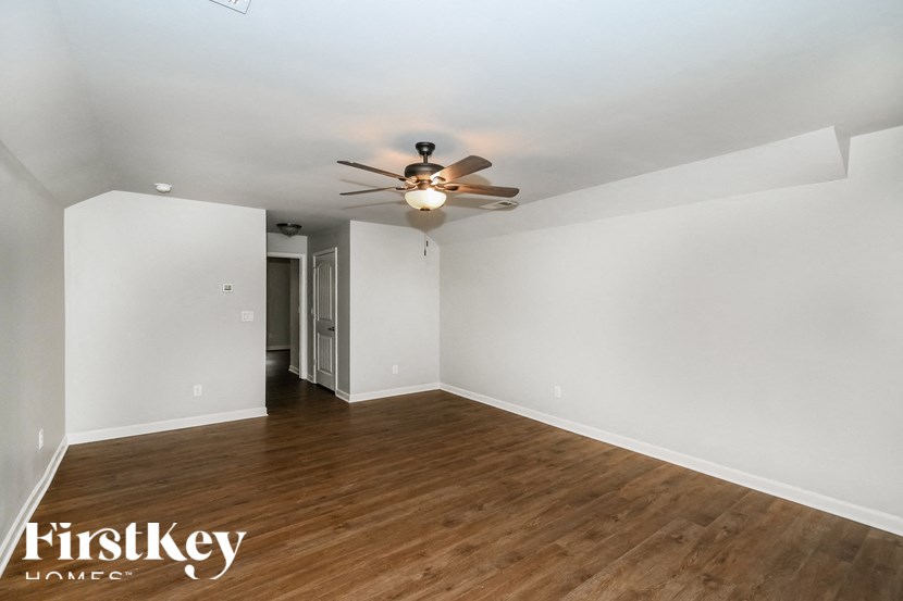 a living room with white walls and a ceiling fan