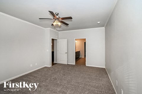 a living room with a ceiling fan and a carpet