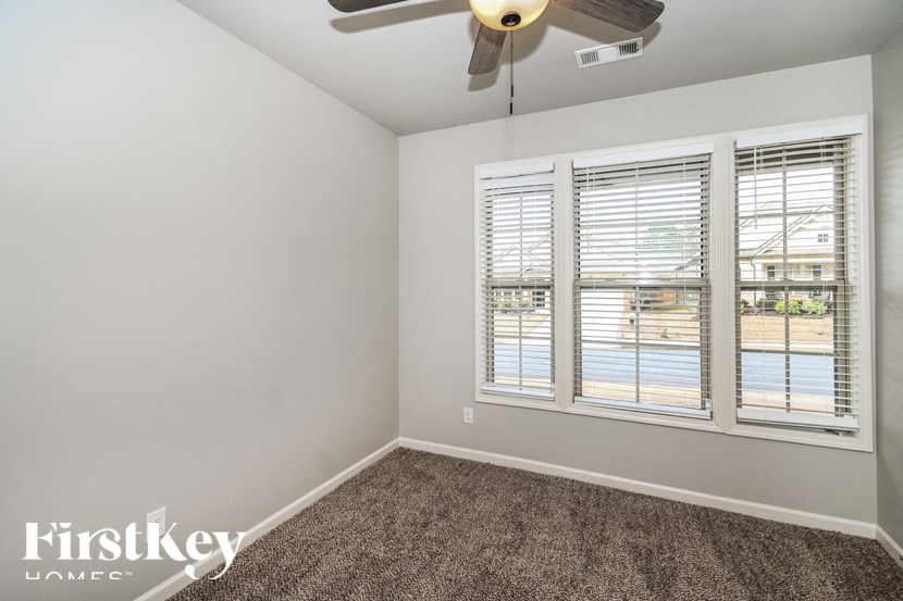 an empty room with a ceiling fan and three windows