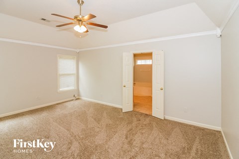 a bedroom with a ceiling fan and a door to a closet