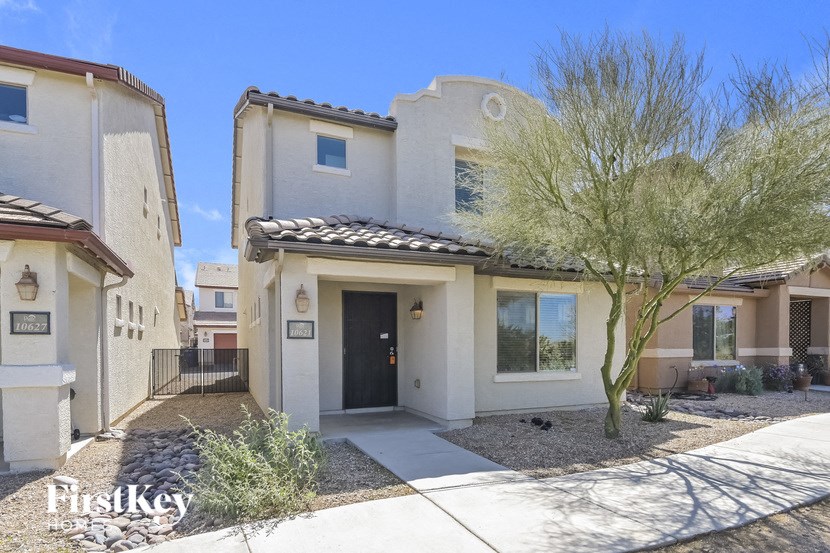 A house with a black gate and a tree in front of it.