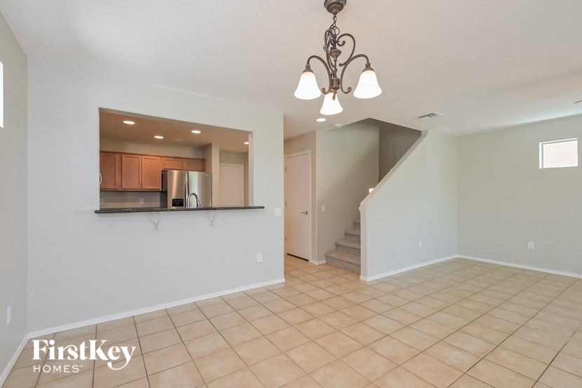 A spacious room with a chandelier and a staircase.