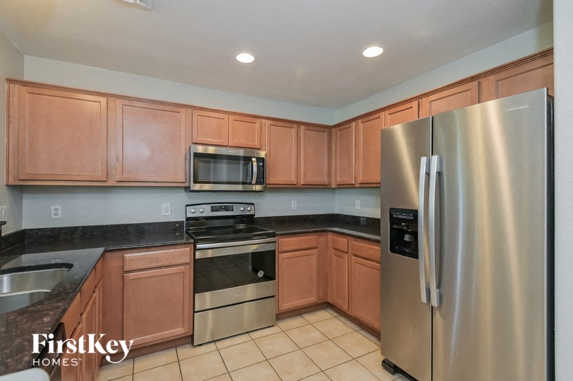 A kitchen with a stainless steel refrigerator and wooden cabinets.