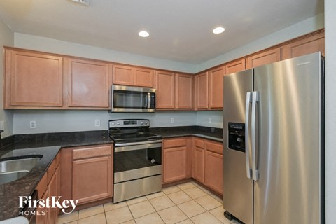 A kitchen with a stainless steel refrigerator and wooden cabinets.