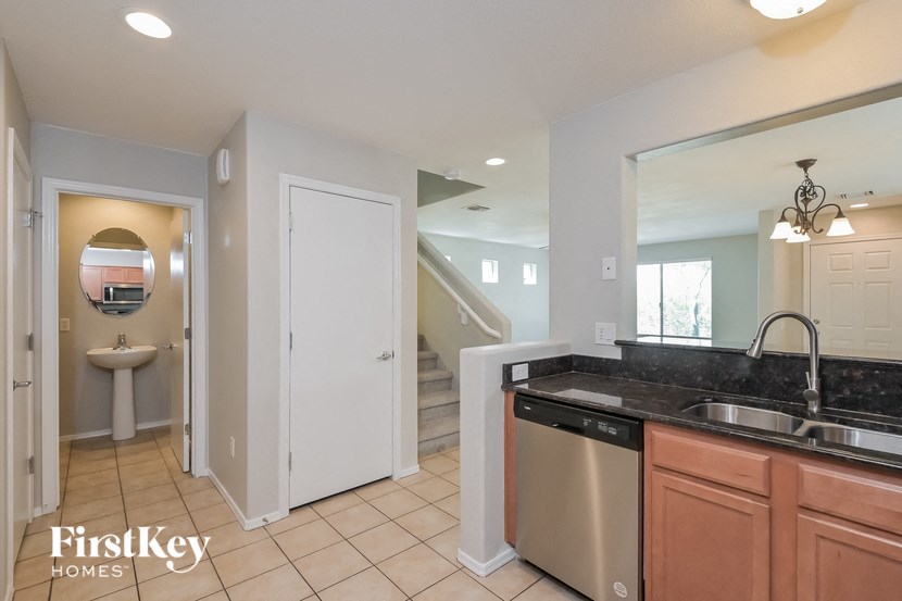 A kitchen with a sink, dishwasher, and a mirror.
