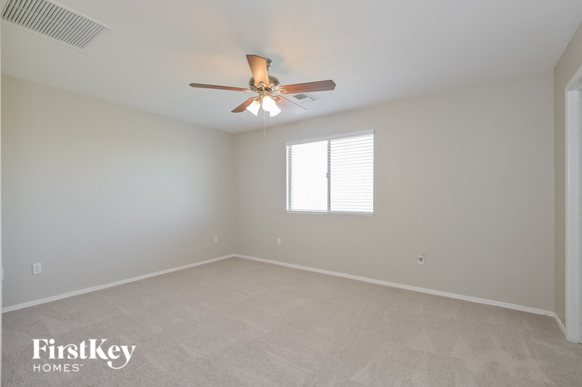 A room with a ceiling fan and a window with blinds.