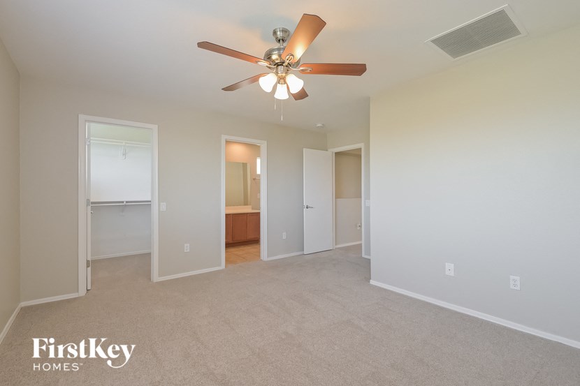 A spacious room with a ceiling fan and beige carpeting.
