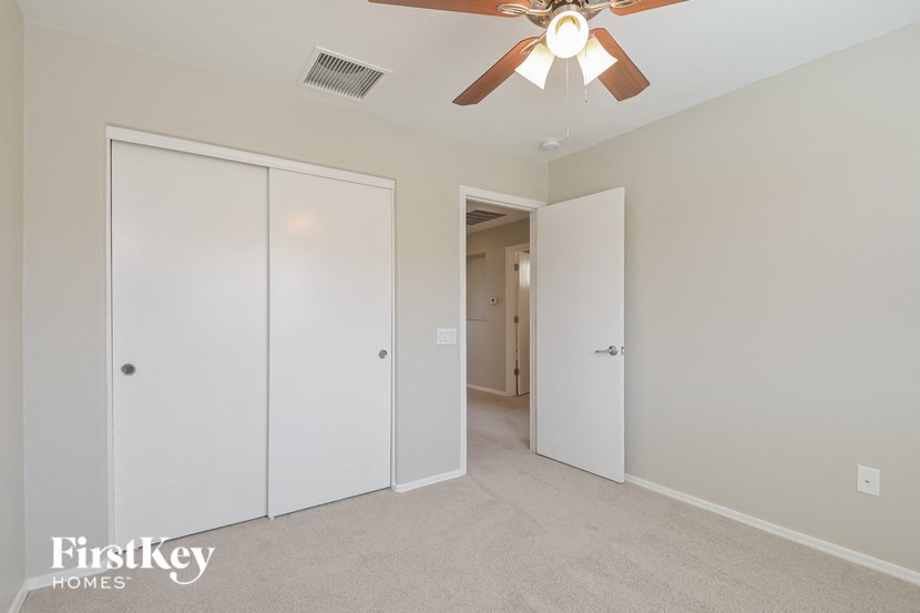 A room with a ceiling fan and three doors.