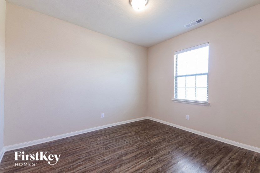 the spacious living room with hardwood flooring and a window