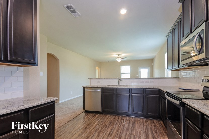 a kitchen with black cabinets and white counter tops and a wood floor