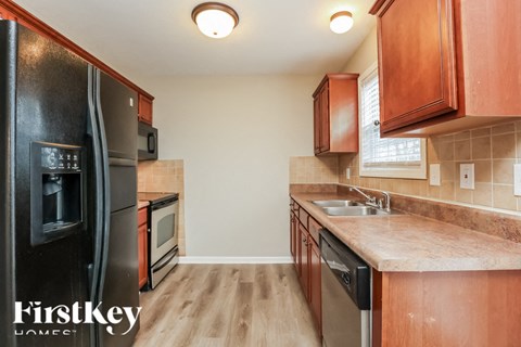 A kitchen with wooden cabinets and a black fridge.