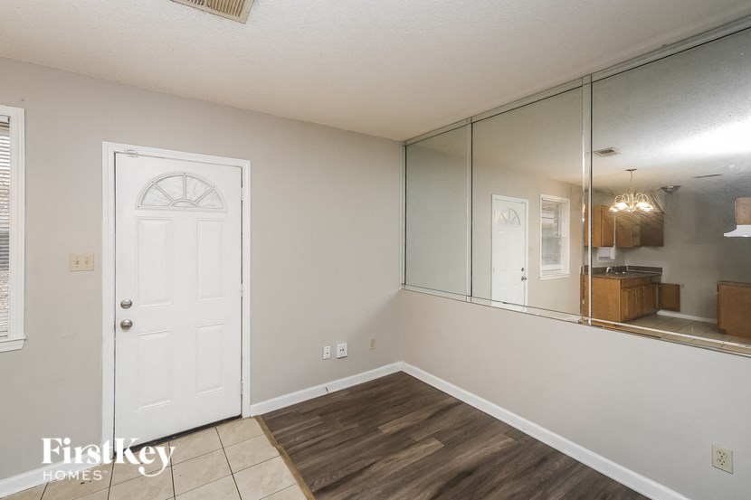 a living room with a white door and a large mirror