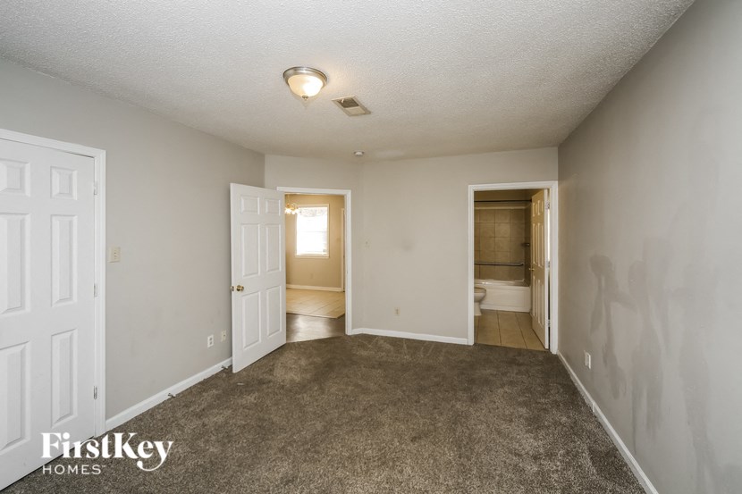 a bedroom with a carpeted floor and a door to a bathroom