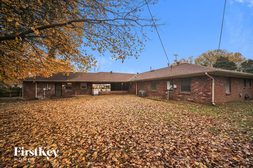 an old brick house in the fall with leaves on the ground