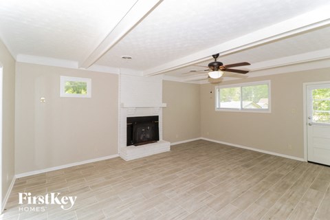 A spacious room with a fireplace and a ceiling fan.