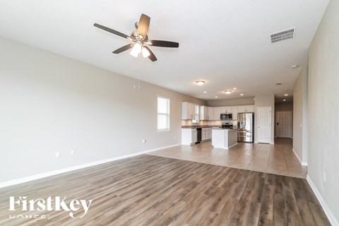 A spacious room with a ceiling fan and wooden flooring.