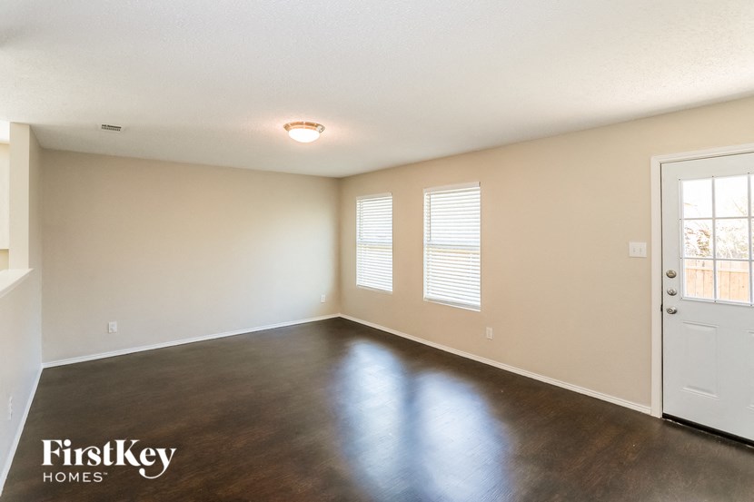 the living room of an empty house with wood flooring and a white door