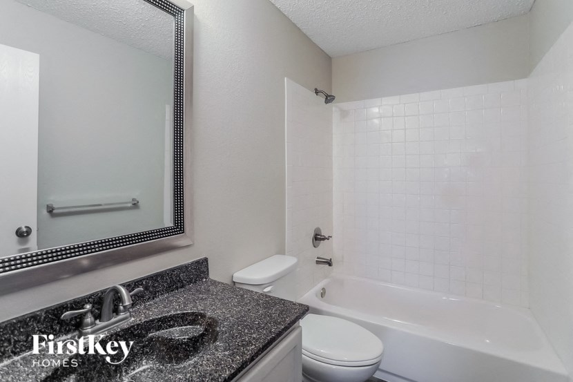 a bathroom with a white tub and a sink and a mirror