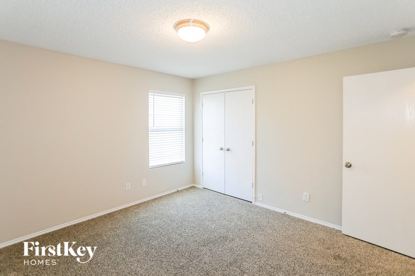 a spacious living room with carpet and a door to a closet