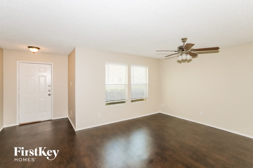 an empty living room with a ceiling fan and a window