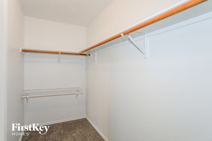 a walk in closet with a white wall and a hanging rail on the wall
