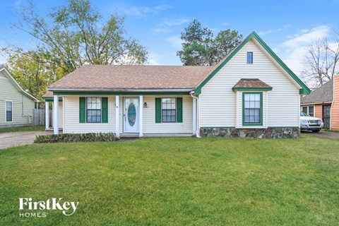 a white house with green shutters and a grassy yard