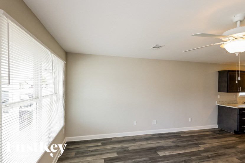 A room with a ceiling fan and a window with blinds.