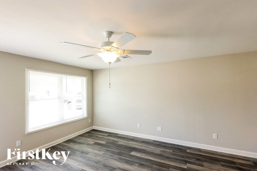 A room with a ceiling fan and wooden flooring.