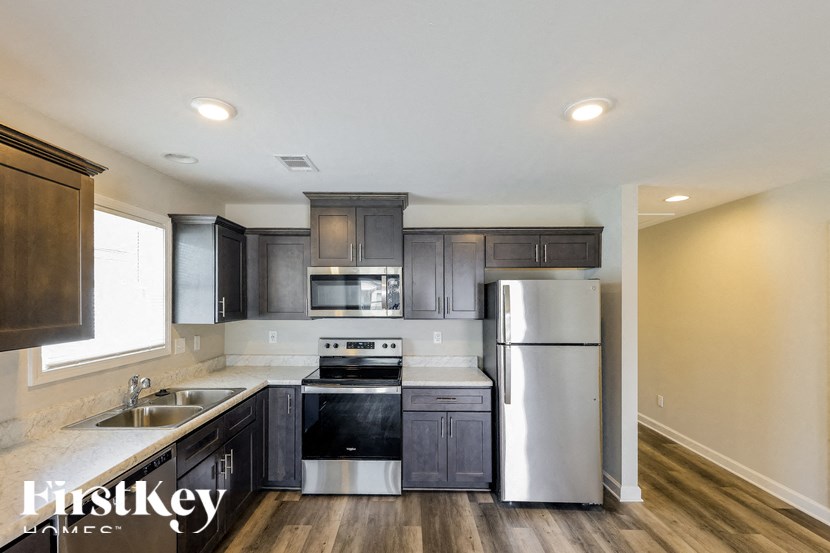 A kitchen with a stainless steel refrigerator and a stove top oven.
