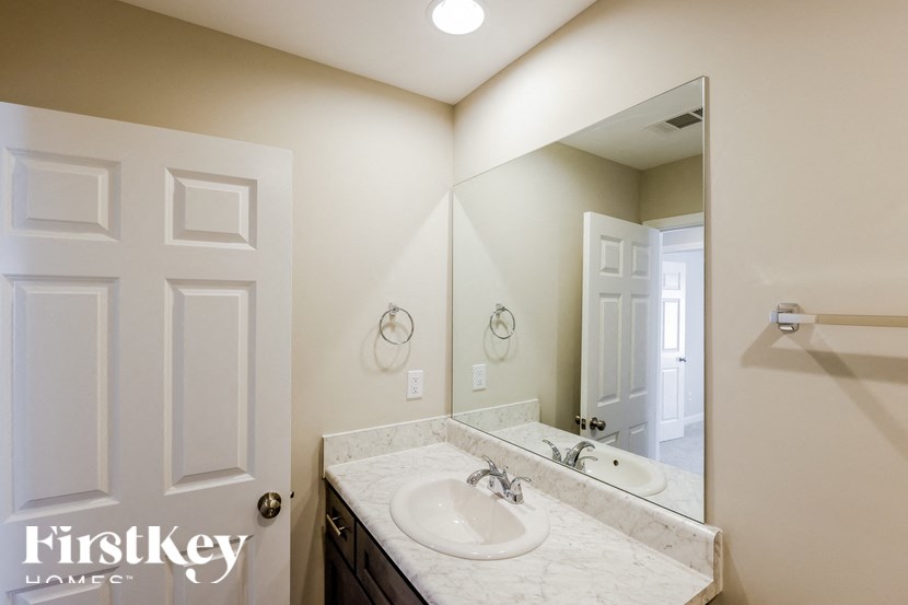 A bathroom with a sink, mirror, and a door.