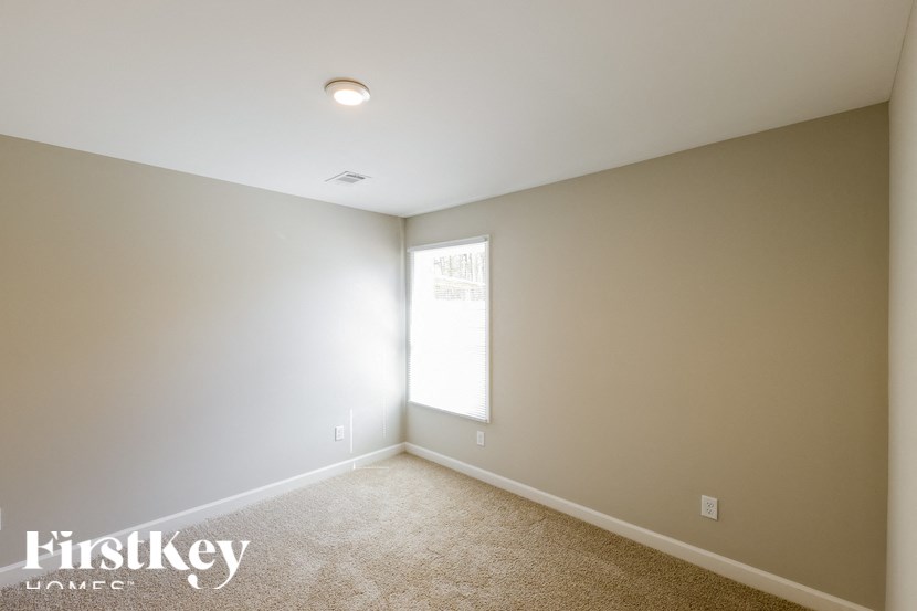A room with a carpet floor and a window letting in light.
