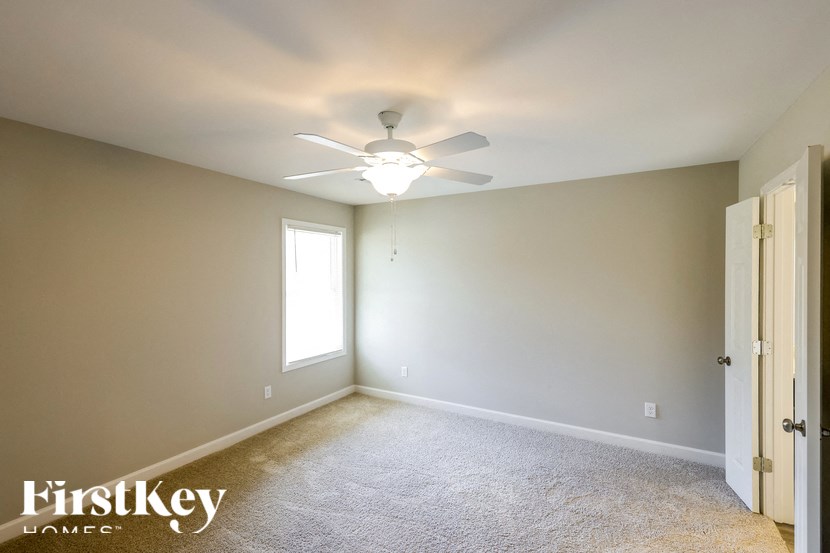 A room with a carpeted floor and a ceiling fan.
