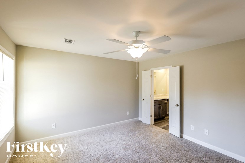 A spacious room with a ceiling fan and a doorway leading to another room.