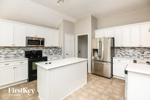 A kitchen with white cabinets and a tiled backsplash.