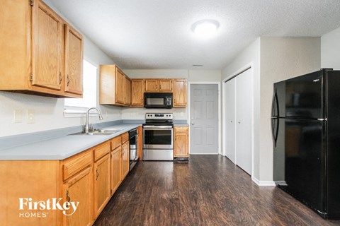 a kitchen with wooden cabinets and a black refrigerator
