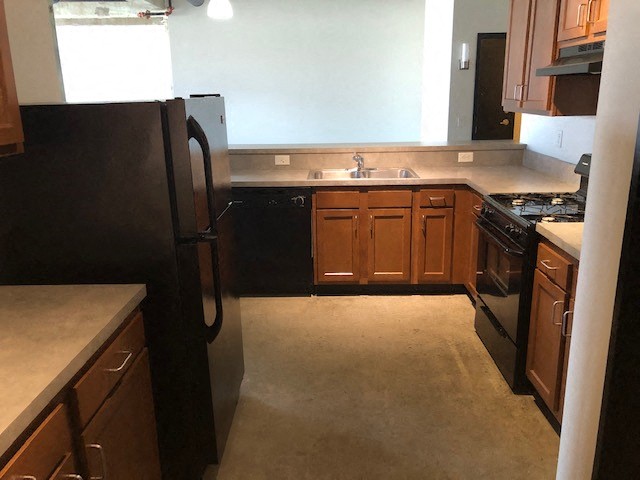 a kitchen with wooden cabinets and a black refrigerator
