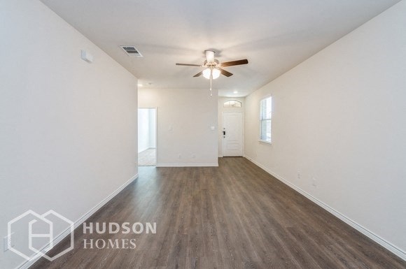 an empty living room with white walls and a ceiling fan