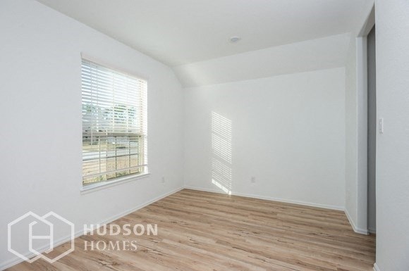 a room with white walls and wood flooring and a window