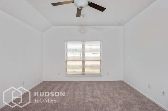an empty living room with a ceiling fan and a window