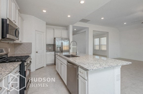 a kitchen with white cabinets and a marble counter top