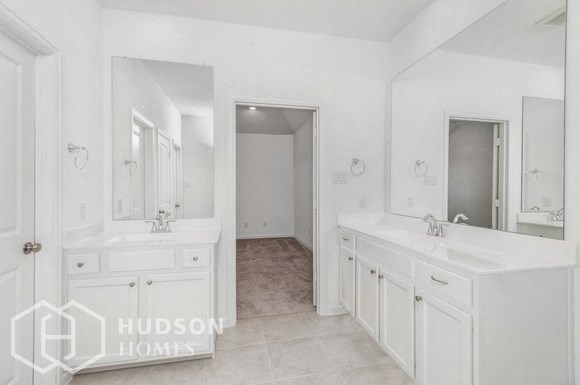 a large white bathroom with two sinks and a large mirror