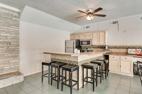 a kitchen with a long counter top with bar stools