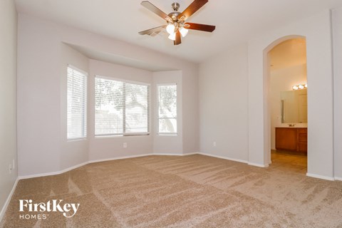 a spacious living room with carpet and a ceiling fan